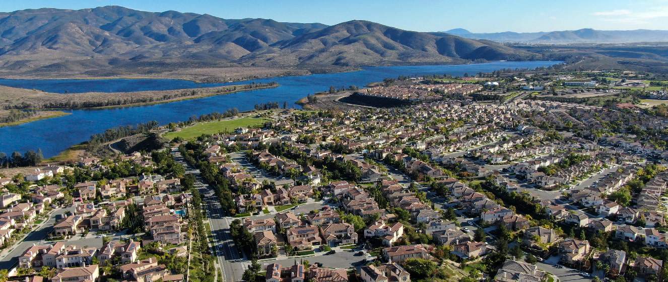 Aerial view of identical residential subdivision house with big lake and mountain on the background during sunny day in Chula Vista
