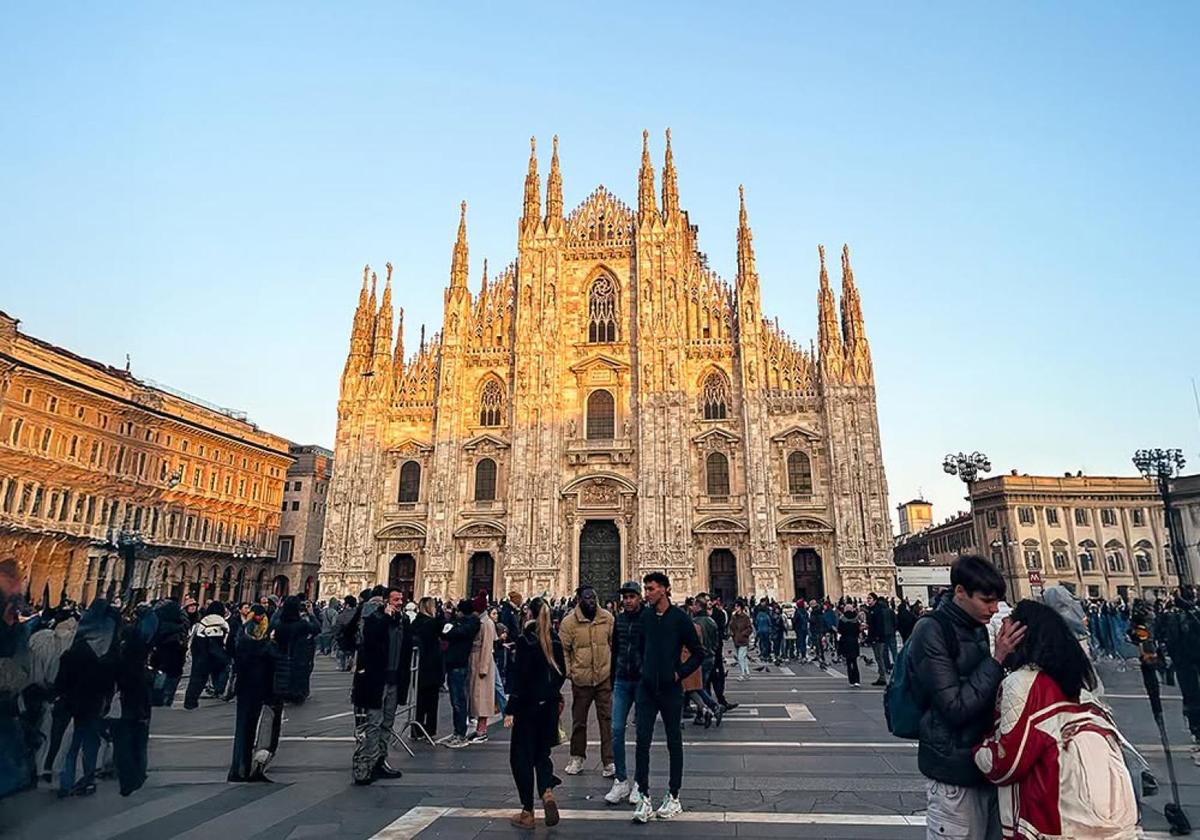 Crowd walking in front of Milan Cathedral at sunset