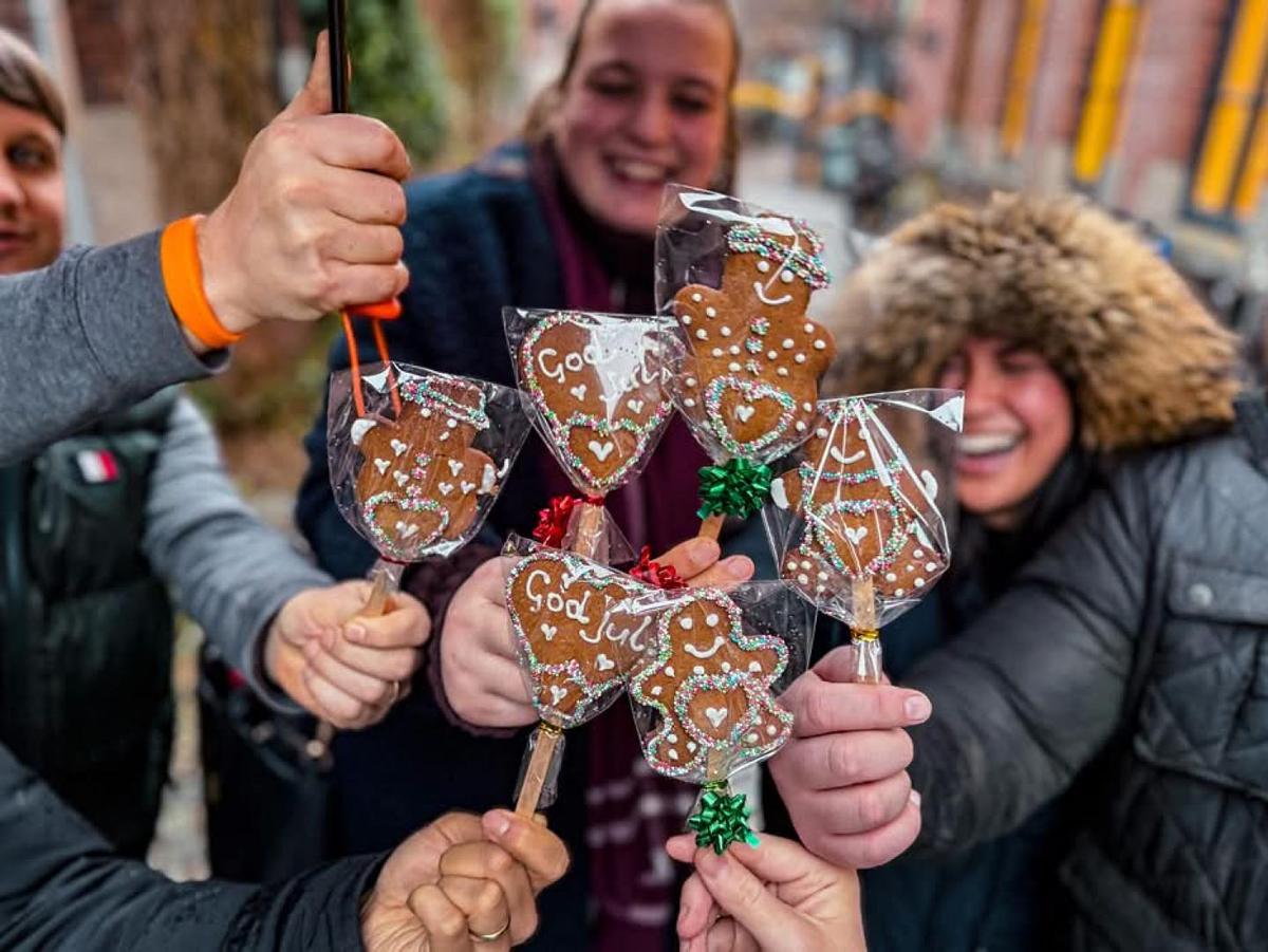 Guests holding decorated gingerbread cookies together during a winter food tour