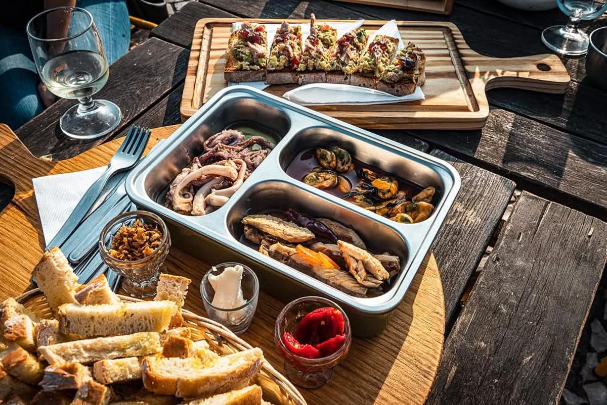 Tapas spread with grilled meats, bread, and small plates on a wooden table