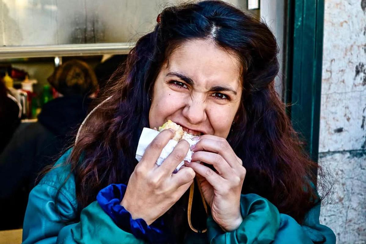 Guest taking a big bite of a sandwich during a street food stop