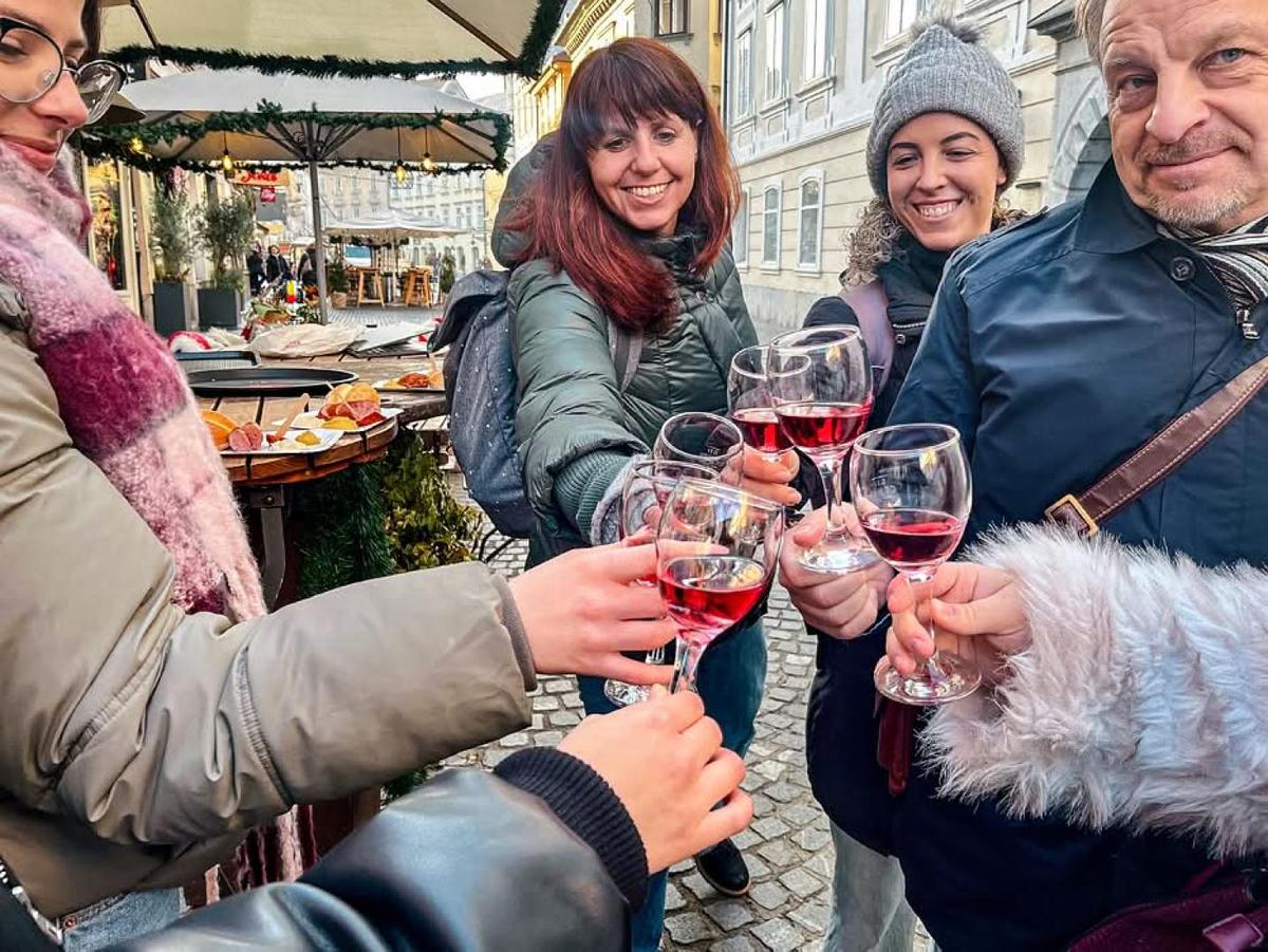 Group of guests toasting red wine glasses outdoors at a market