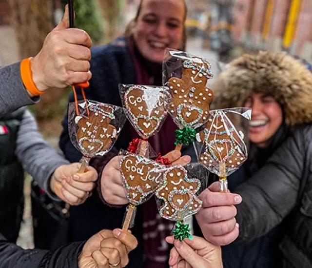 Group holding decorated gingerbread cookies during a festive food tour
