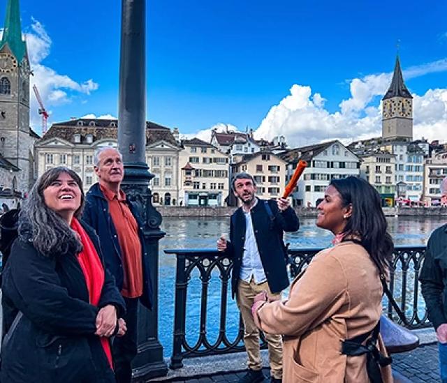 Tour guide speaking to guests by a riverside during a city food tour