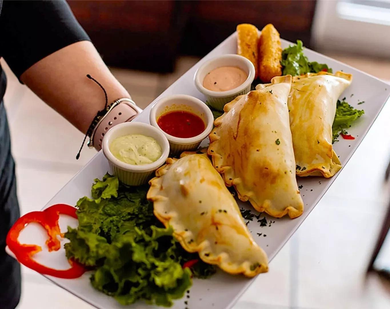 Close up of empanadas served with dipping sauces during a food tour stop